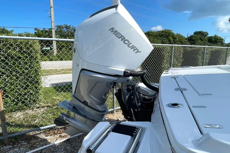 Slide: The Image of 2026 Blackfin 242HB boat with Mercury outboard motor, parked near chain-link fence. - 36
