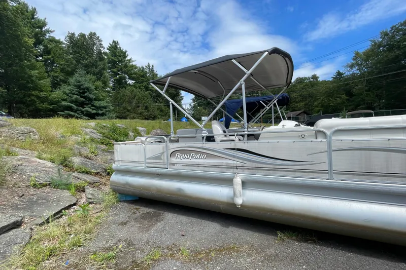 Slide: The Image of 2002 Godfrey Aqua Patio 2424DF pontoon boat on land, surrounded by trees and rocks. - 3