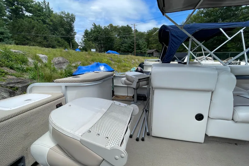 Slide: The Image of 2002 Godfrey Aqua Patio 2424DF pontoon boat interior with seating and canopy, set in a natural landscape. - 6