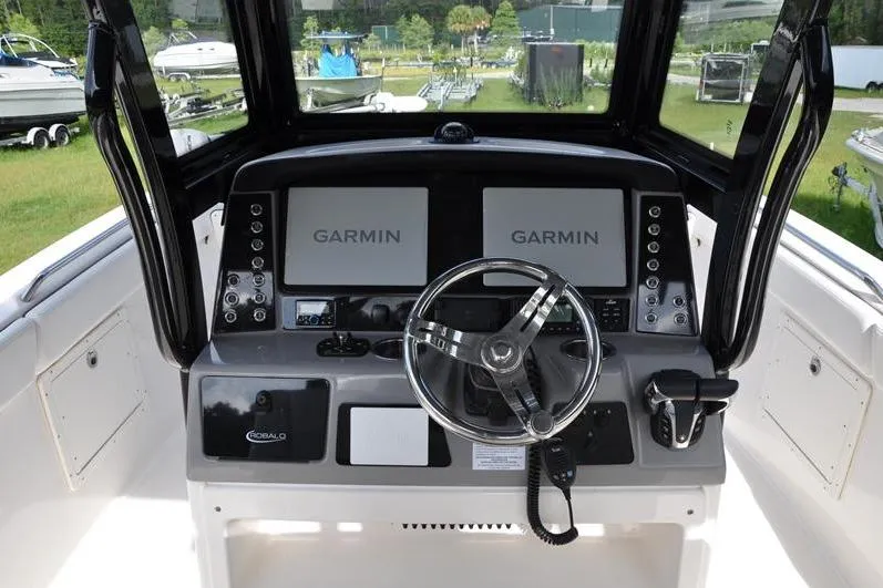 Slide: The Image of 2023 Robalo R272 Center Console boat dashboard with dual Garmin displays and steering wheel. - 15