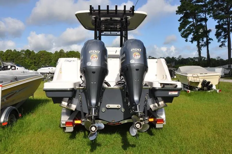 Slide: The Image of 2023 Robalo R272 Center Console boat with dual Yamaha 200 engines, parked on grass. - 2