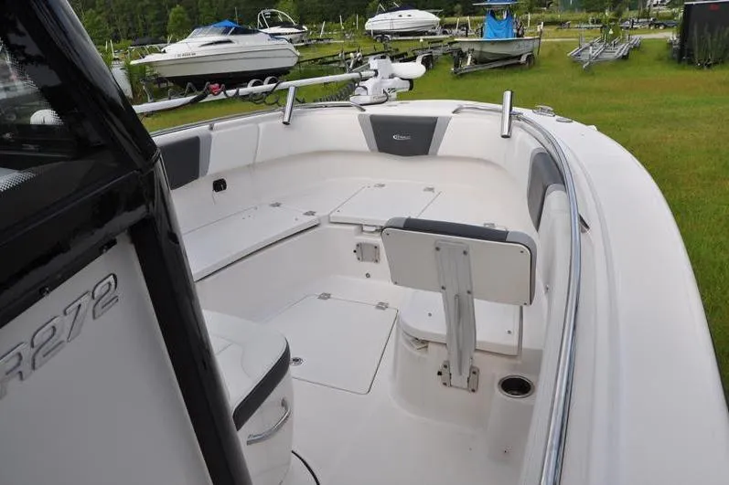 Slide: The Image of 2023 Robalo R272 Center Console boat interior with seating and storage, parked outdoors. - 28