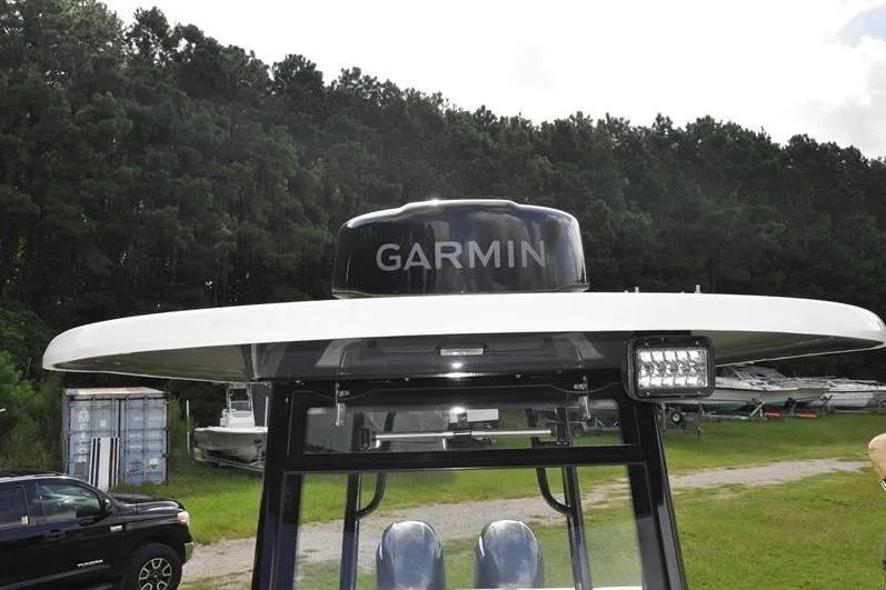 Slide: The Image of 2023 Robalo R272 Center Console with Garmin radar, parked outdoors near trees. - 34