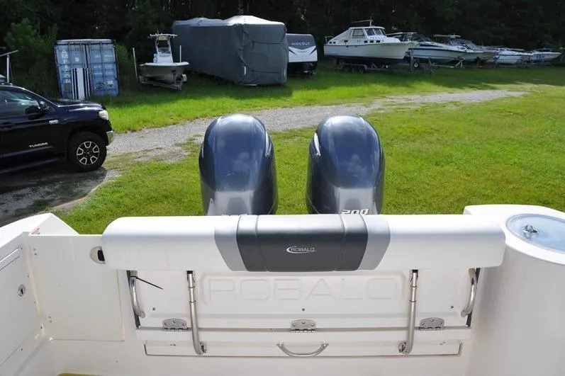 Slide: The Image of 2023 Robalo R272 Center Console boat with dual engines in a grassy storage area. - 9