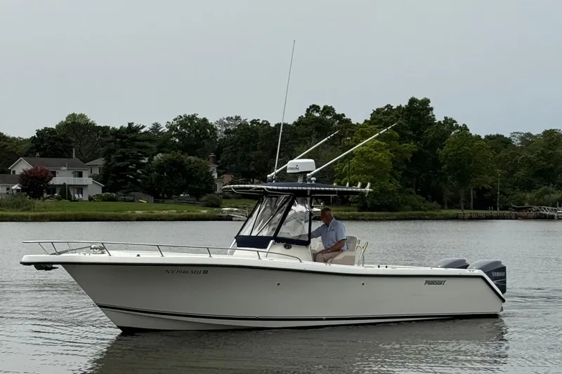 Slide: The Image of 2008 Pursuit C 280 Center Console boat cruising on a calm lake near houses. - 2
