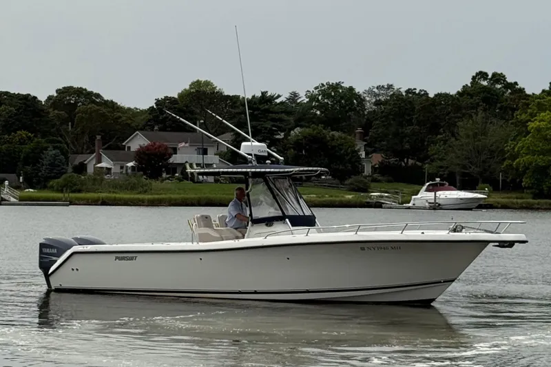 Slide: The Image of 2008 Pursuit C 280 Center Console boat cruising on a calm lake near houses and trees. - 3