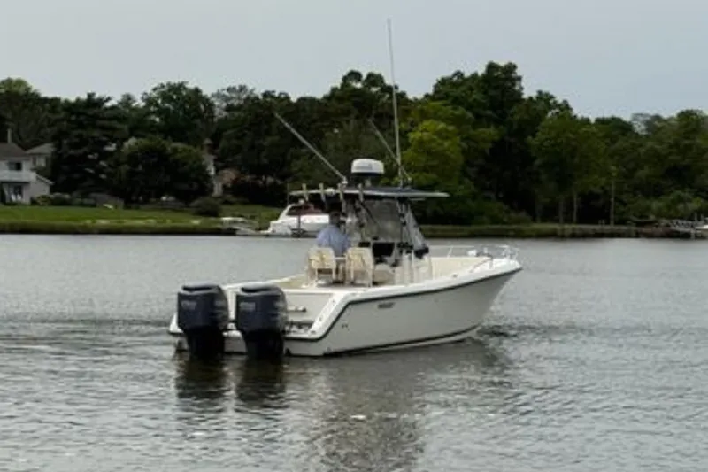 Slide: The Image of 2008 Pursuit C 280 Center Console boat cruising on a calm lake near shoreline homes. - 4