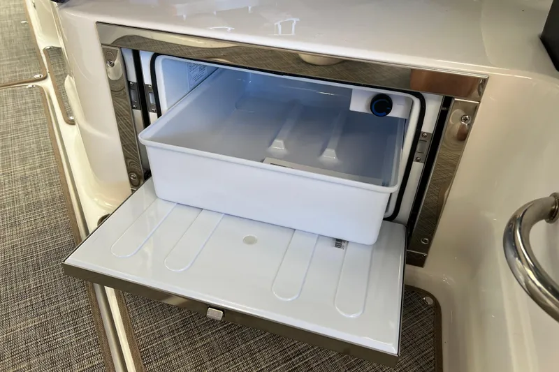 Slide: The Image of Built-in cooler on 2025 Sea Ray SLX 280 boat, open with storage tray. - 23