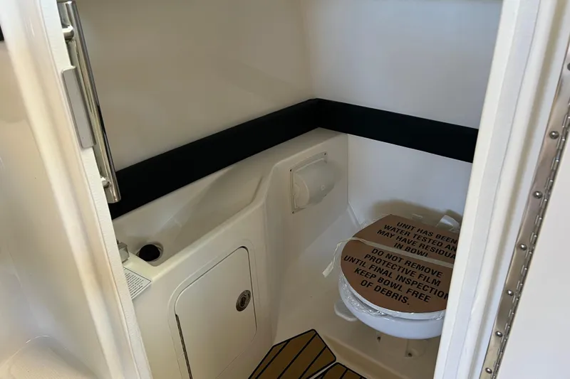 Slide: The Image of 2025 Sea Ray SLX 280 boat bathroom interior with protective film on toilet. - 29