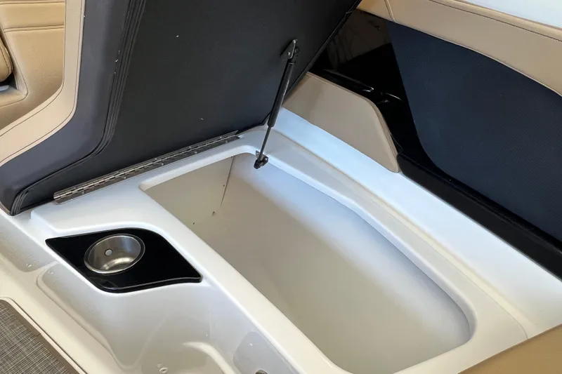 Slide: The Image of 2025 Sea Ray SLX 280 boat storage compartment with cup holder, open lid view. - 34