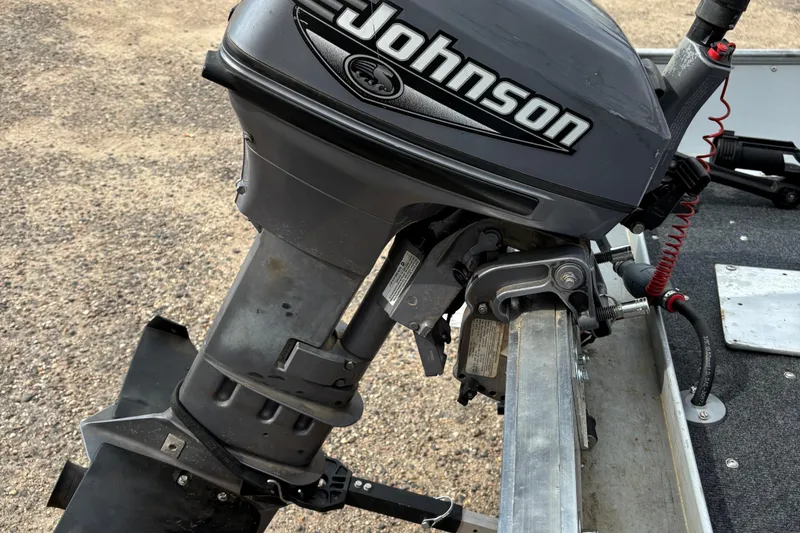 Slide: The Image of 1999 Lund SSV 14 Tiller boat with Johnson outboard motor, parked on gravel. - 5