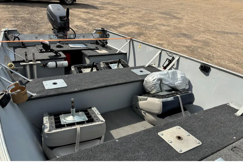 Slide: The Image of 1999 Lund SSV 14 Tiller boat interior with motor and seating, parked on gravel. - 8