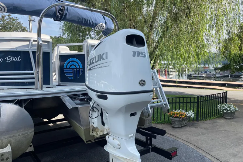 Slide: The Image of 2023 Nepallo 24QL Sport Toon with Suzuki 115 outboard motor, docked near a marina. - 3