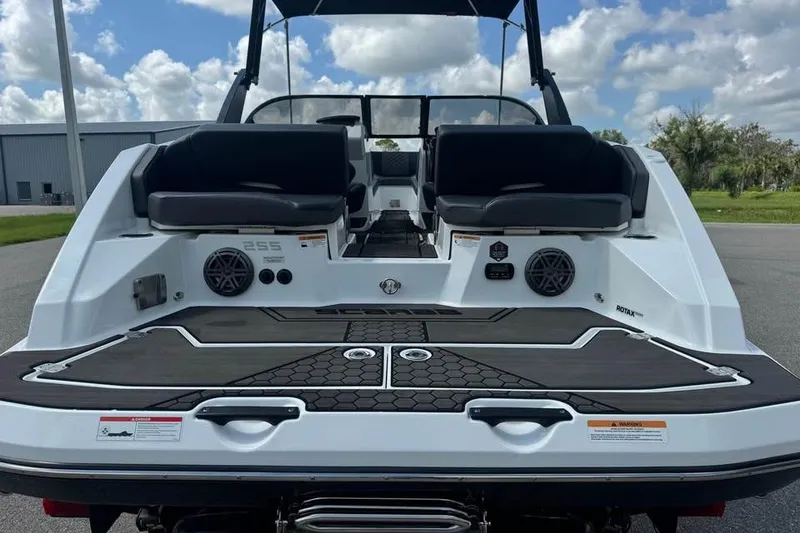 Slide: The Image of 2023 Scarab 255 ID boat rear view with seating and speakers, under a cloudy sky. - 10