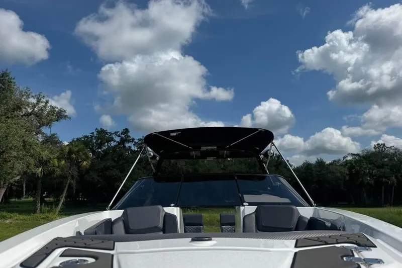 Slide: The Image of 2023 Scarab 255 ID boat with canopy, set against a scenic sky and trees. - 12