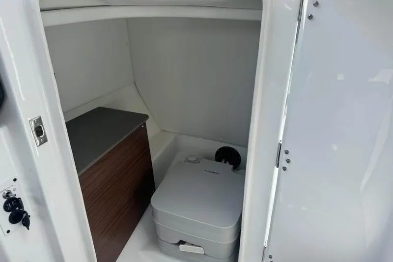 Slide: The Image of Interior of 2023 Scarab 255 ID boat featuring compact marine toilet. - 15