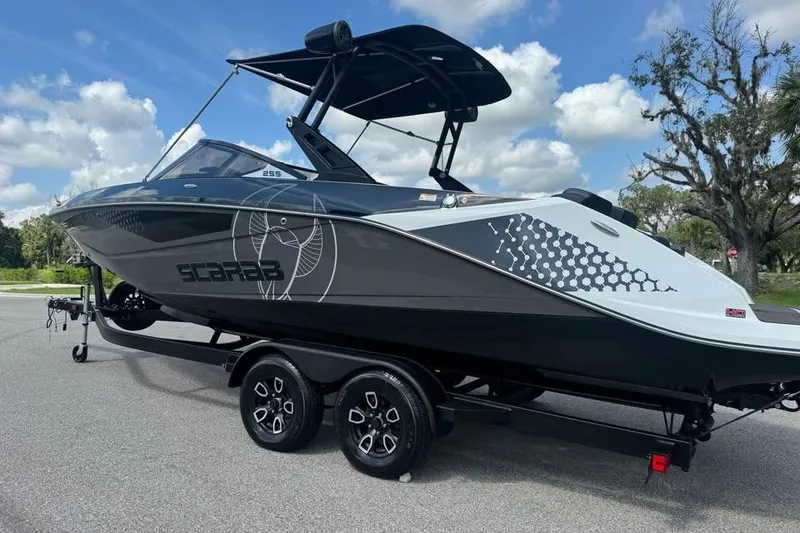 Slide: The Image of 2023 Scarab 255 ID boat on trailer, sleek design, parked outdoors under blue sky. - 4