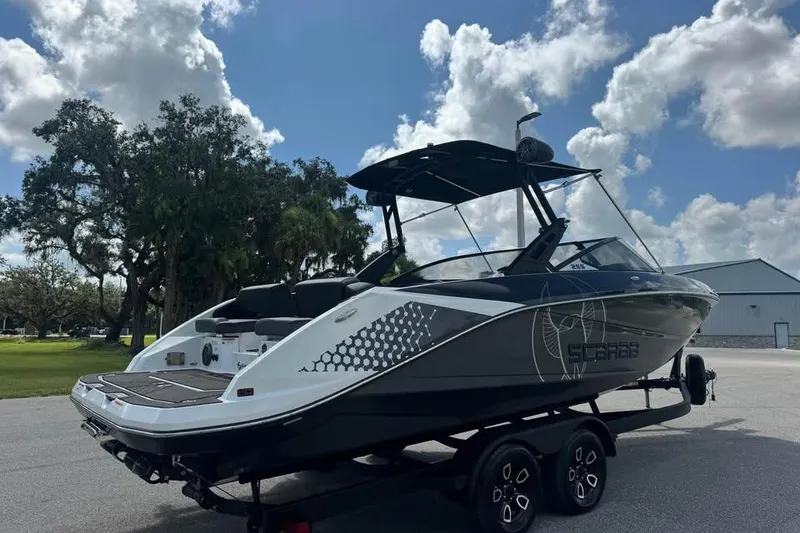 Slide: The Image of 2023 Scarab 255 ID boat on trailer under a blue sky with clouds. - 6