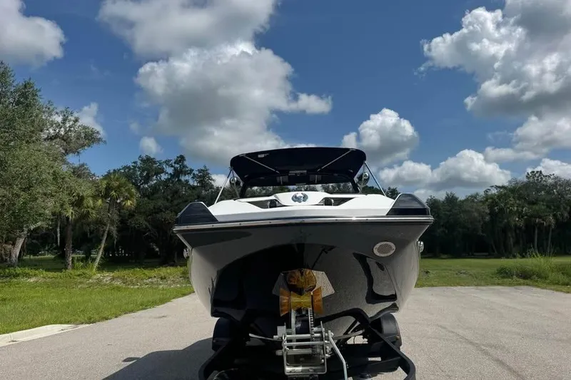 Slide: The Image of 2023 Scarab 255 ID boat on trailer under a blue sky with clouds. - 8