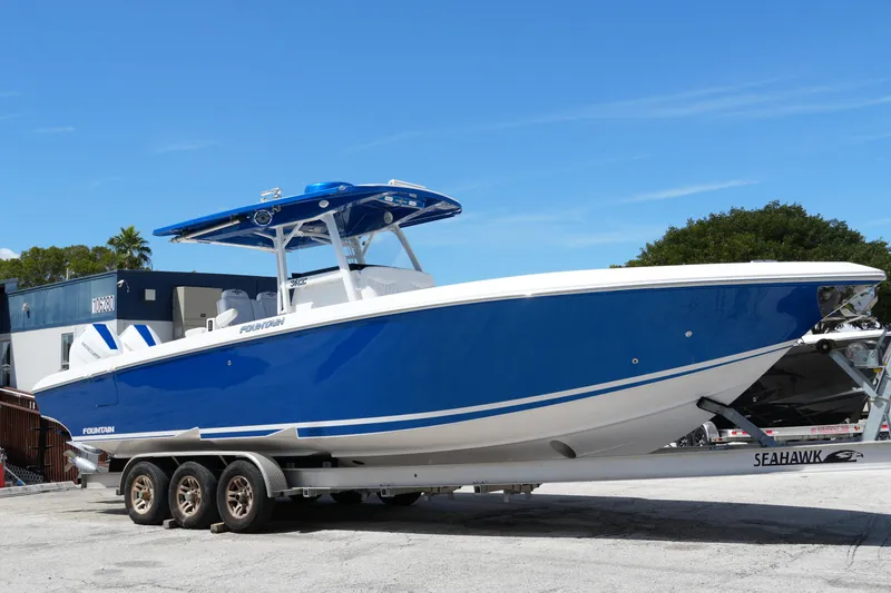 Slide: The Image of 2023 Fountain 34 Center Console boat on trailer, blue and white design, parked outdoors. - 3