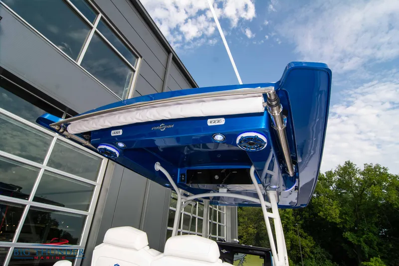 Slide: The Image of 2023 Fountain 34 CC boat with blue hardtop and speakers, near modern building. - 30