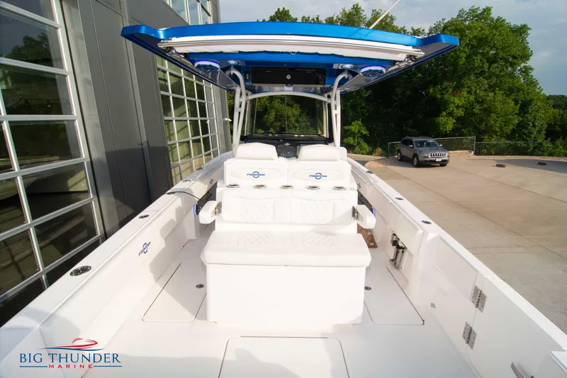 Slide: The Image of 2023 Fountain 34 CC boat with blue canopy, docked near a modern building. - 36