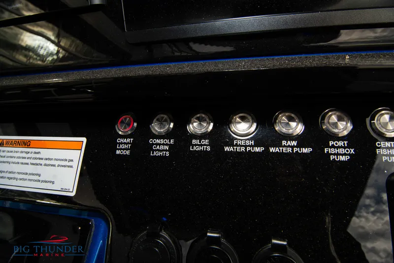 Slide: The Image of Control panel of 2023 Fountain 34 CC boat with various switches and warning label. - 52