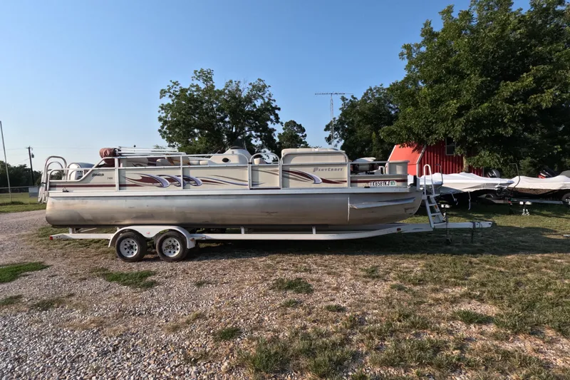 Slide: The Image of 2006 PlayCraft Sunfish 2400 pontoon boat on trailer, parked outdoors near trees. - 0