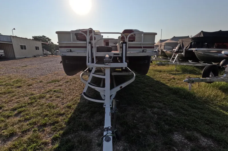Slide: The Image of 2006 PlayCraft Sunfish 2400 pontoon boat on trailer in outdoor storage area. - 2