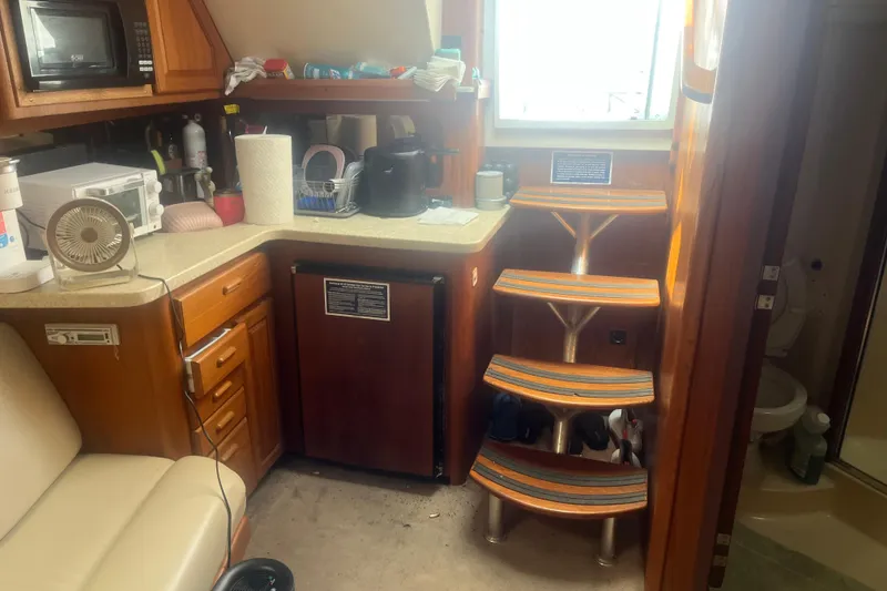 Slide: The Image of 1998 Luhrs 36 Open interior with kitchenette, wooden stairs, and compact appliances. - 6