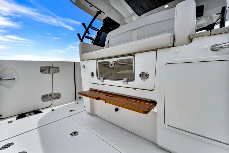 Slide: The Image of 2023 Boston Whaler 350 Realm interior, featuring sleek seating and storage against a clear blue sky. - 15