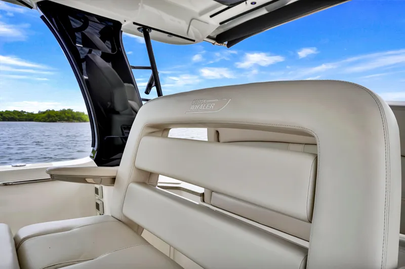 Slide: The Image of 2023 Boston Whaler 350 Realm interior with luxurious seating, overlooking serene water and blue sky. - 19