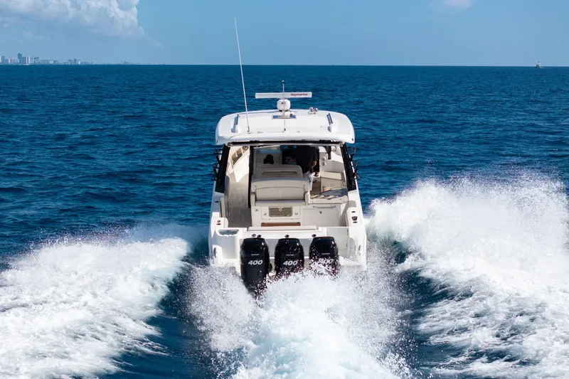 Slide: The Image of 2023 Boston Whaler 350 Realm cruising on open ocean, rear view with powerful engines. - 27