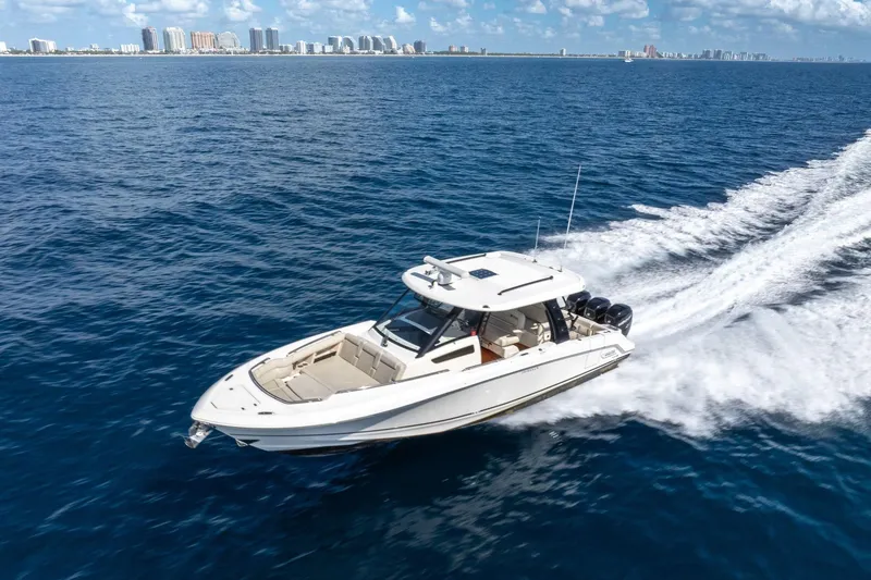 Slide: The Image of 2023 Boston Whaler 350 Realm cruising on open ocean with city skyline in background. - 28