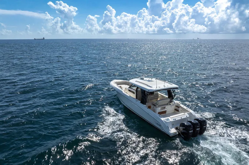 Slide: The Image of 2023 Boston Whaler 350 Realm cruising on open ocean under a bright, cloudy sky. - 4