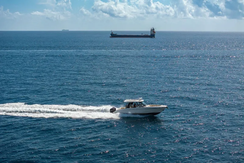 Slide: The Image of 2023 Boston Whaler 350 Realm cruising on open ocean with cargo ship in background. - 5