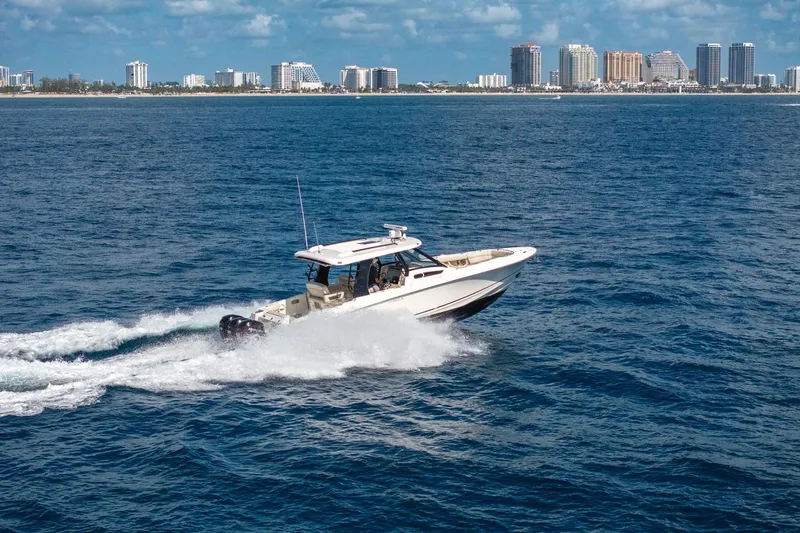 Slide: The Image of 2023 Boston Whaler 350 Realm cruising on ocean with city skyline in background. - 6