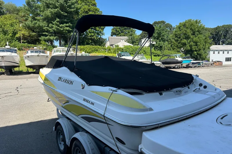 Slide: The Image of 2006 Larson Senza 206 boat with cover, parked on a trailer in a marina. - 15