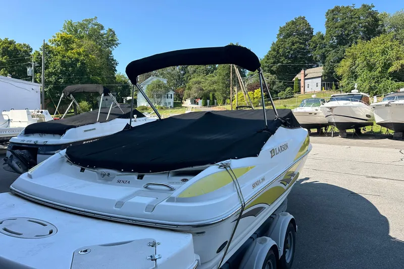 Slide: The Image of 2006 Larson Senza 206 boat with cover, parked on trailer in sunny outdoor setting. - 16