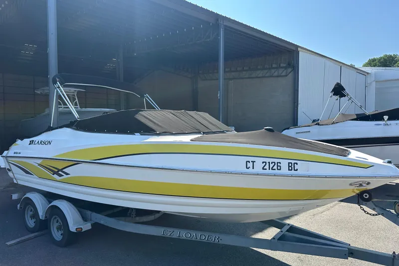Slide: The Image of 2006 Larson Senza 206 boat with yellow accents on a trailer in a storage area. - 17