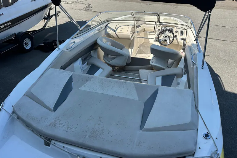 Slide: The Image of 2006 Larson Senza 206 boat interior with seating and steering wheel, parked on pavement. - 6