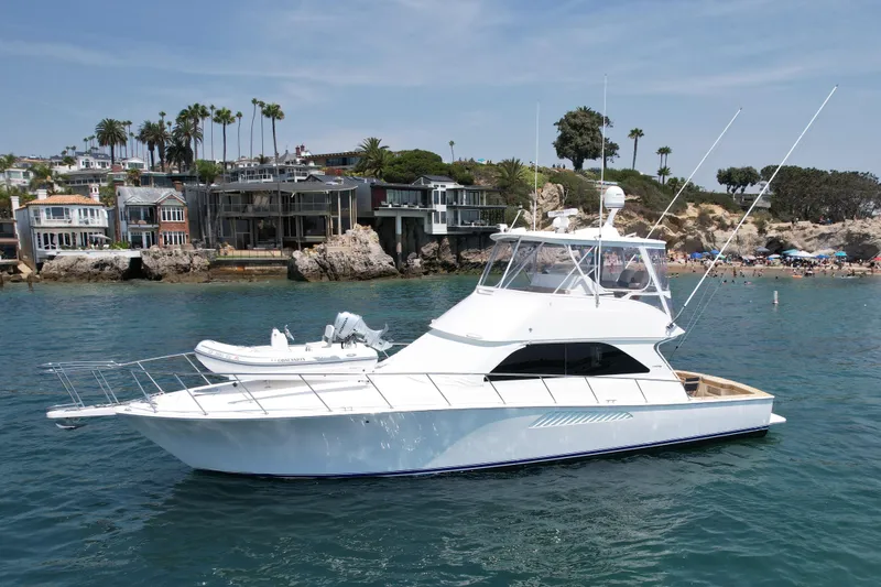 Slide: The Image of 2005 Viking 48 Convertible yacht on calm water near coastal homes. - 4