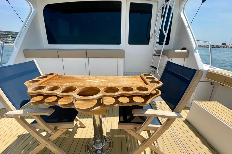 Slide: The Image of 2005 Viking 48 Convertible yacht deck with wooden table and chairs, ocean view. - 49