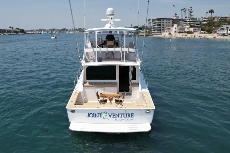 Slide: The Image of 2005 Viking 48 Convertible yacht on water near coastal buildings. - 6