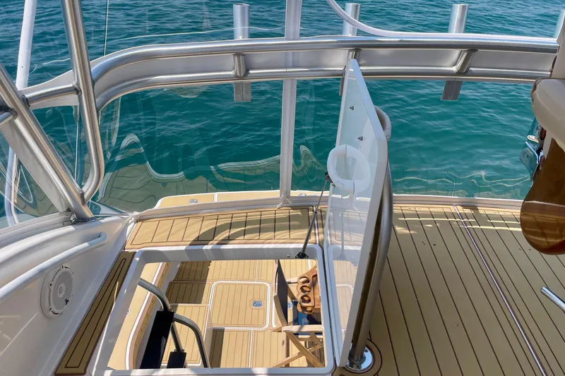 Slide: The Image of 2005 Viking 48 Convertible yacht deck with open hatch, overlooking clear blue water. - 64