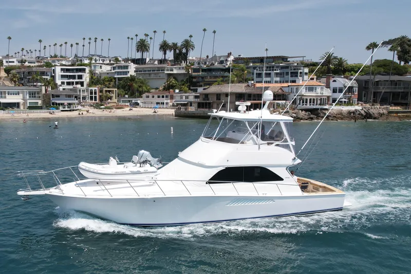 Slide: The Image of 2005 Viking 48 Convertible yacht cruising near a coastal residential area. - 7