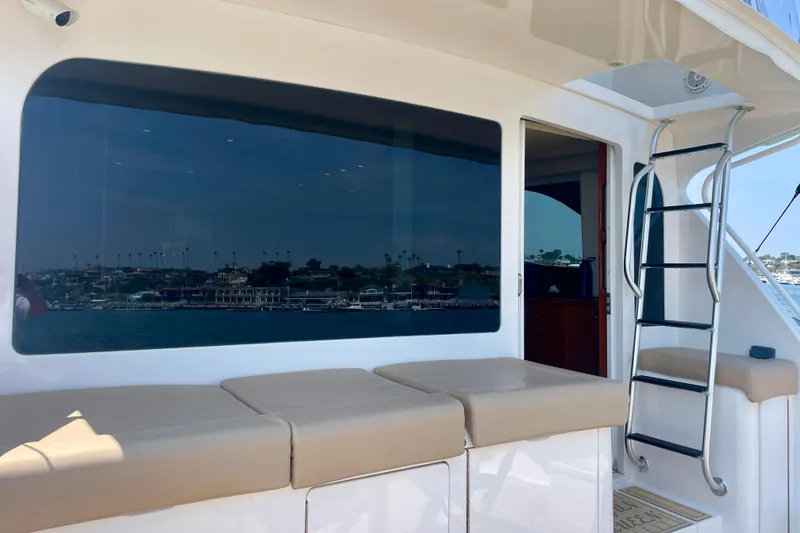 Slide: The Image of 2005 Viking 48 Convertible yacht with cushioned seating and ladder, docked by the waterfront. - 70