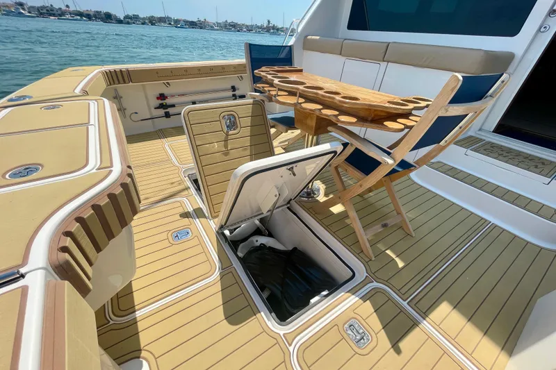 Slide: The Image of 2005 Viking 48 Convertible yacht deck with open storage, seating, and table by the water. - 81