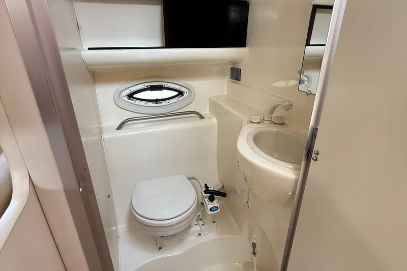 Slide: The Image of 2004 Bayliner 285 boat bathroom with toilet, sink, and porthole window. - 11