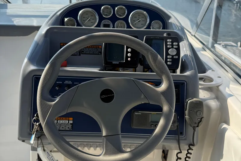 Slide: The Image of Steering wheel and dashboard of a 2004 Bayliner 285 boat with gauges and controls. - 19
